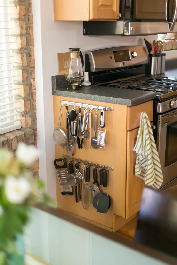 kitchen tools hanging from the side of a cabinet