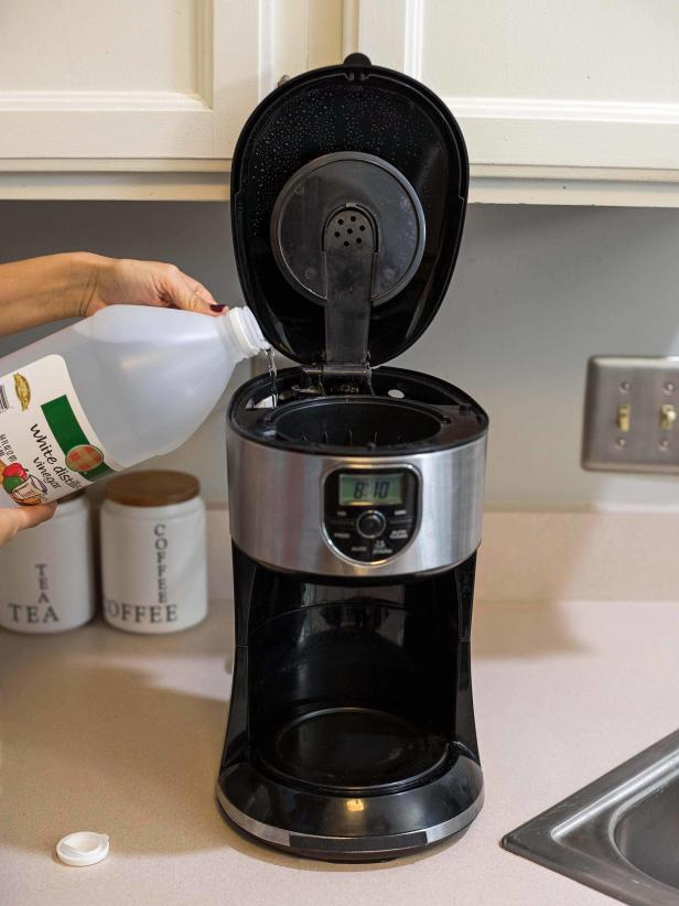 pouring vinegar in the coffee maker to clean it